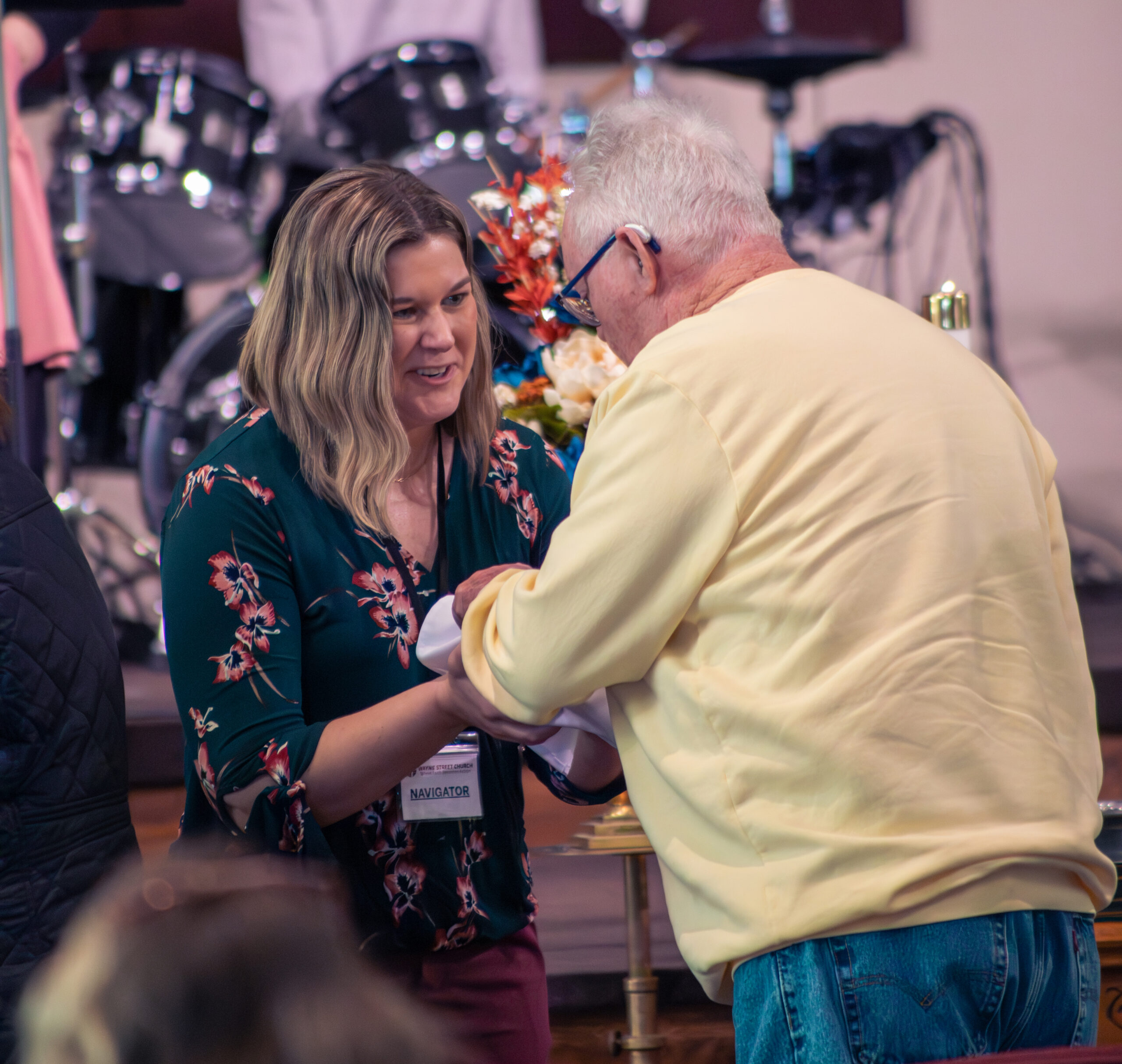 Woman holds out bread to an older adult male for communion in church